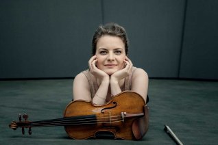 Violinistin Veronika Eberle auf den Ellenbogen gestützt vor ihr ihre Geige