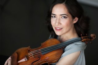 Das Foto zeigt die Violinistin mit Geige vor dunklem Hintergrund.