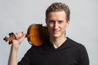 Ein Portr&auml;t des Geigers, der sein Instrument mit seiner rechten Hand auf seine rechte Schulter st&uuml;tzt, vor hellem Hintergrund.